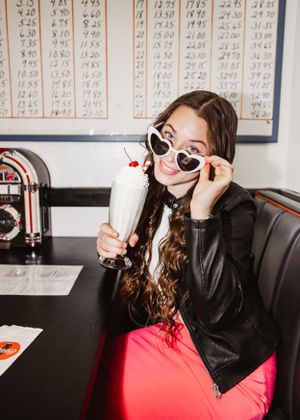 Retro diner scene with milkshake and leather jacket style against vintage menu board background.