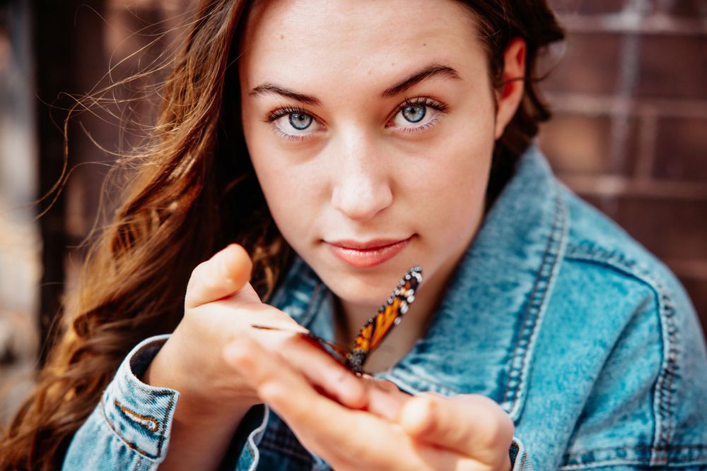 Close up portrait with denim jacket against brick wall background.