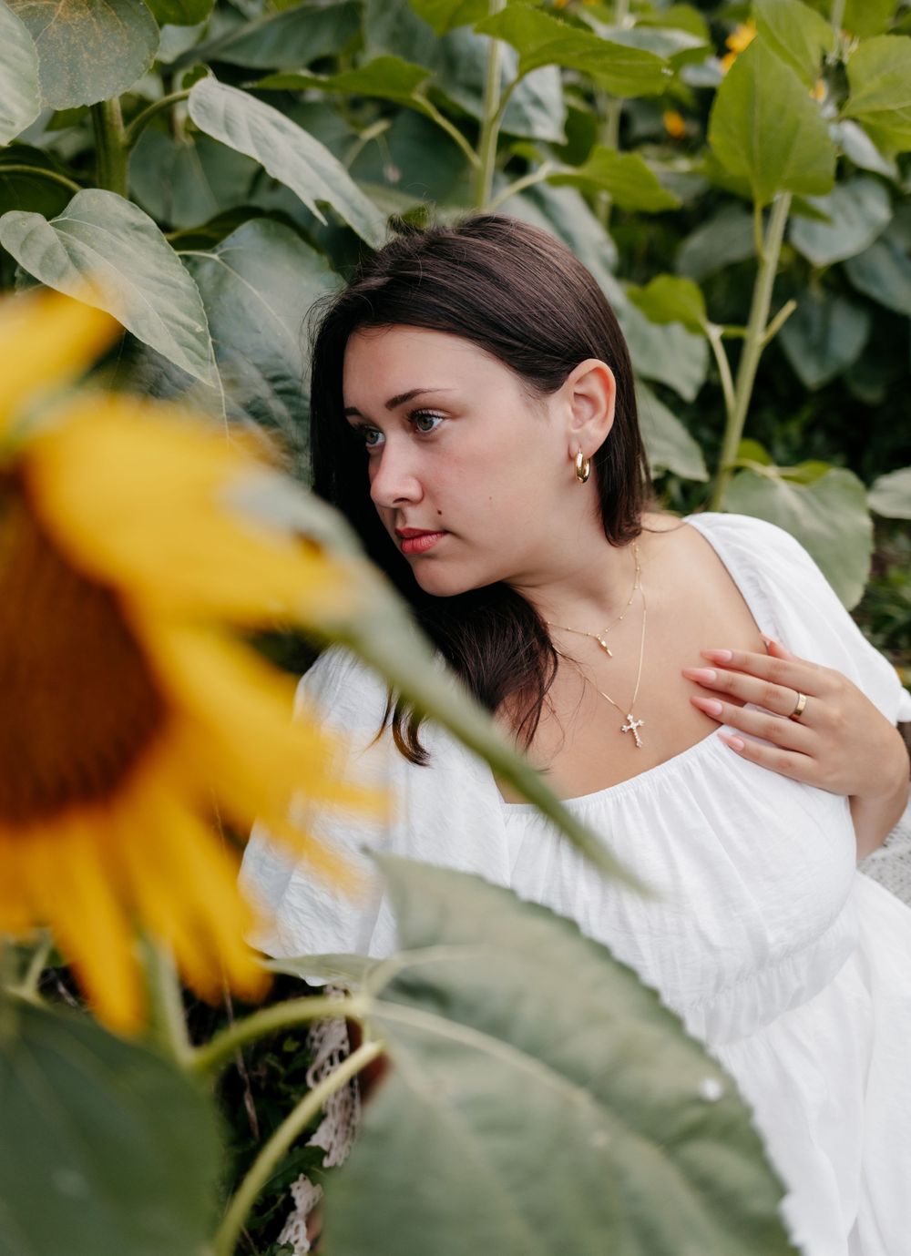 A portrait in a sunflower garden with soft natural lighting and white summer dress.