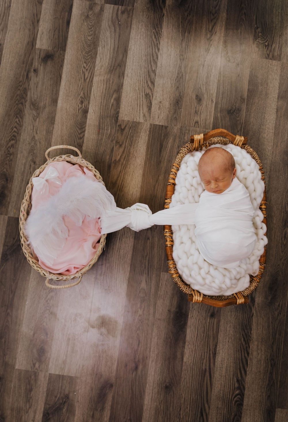 A progression of five aerial shots showing a baby in a pink dress and white dress lying on a wooden floor.