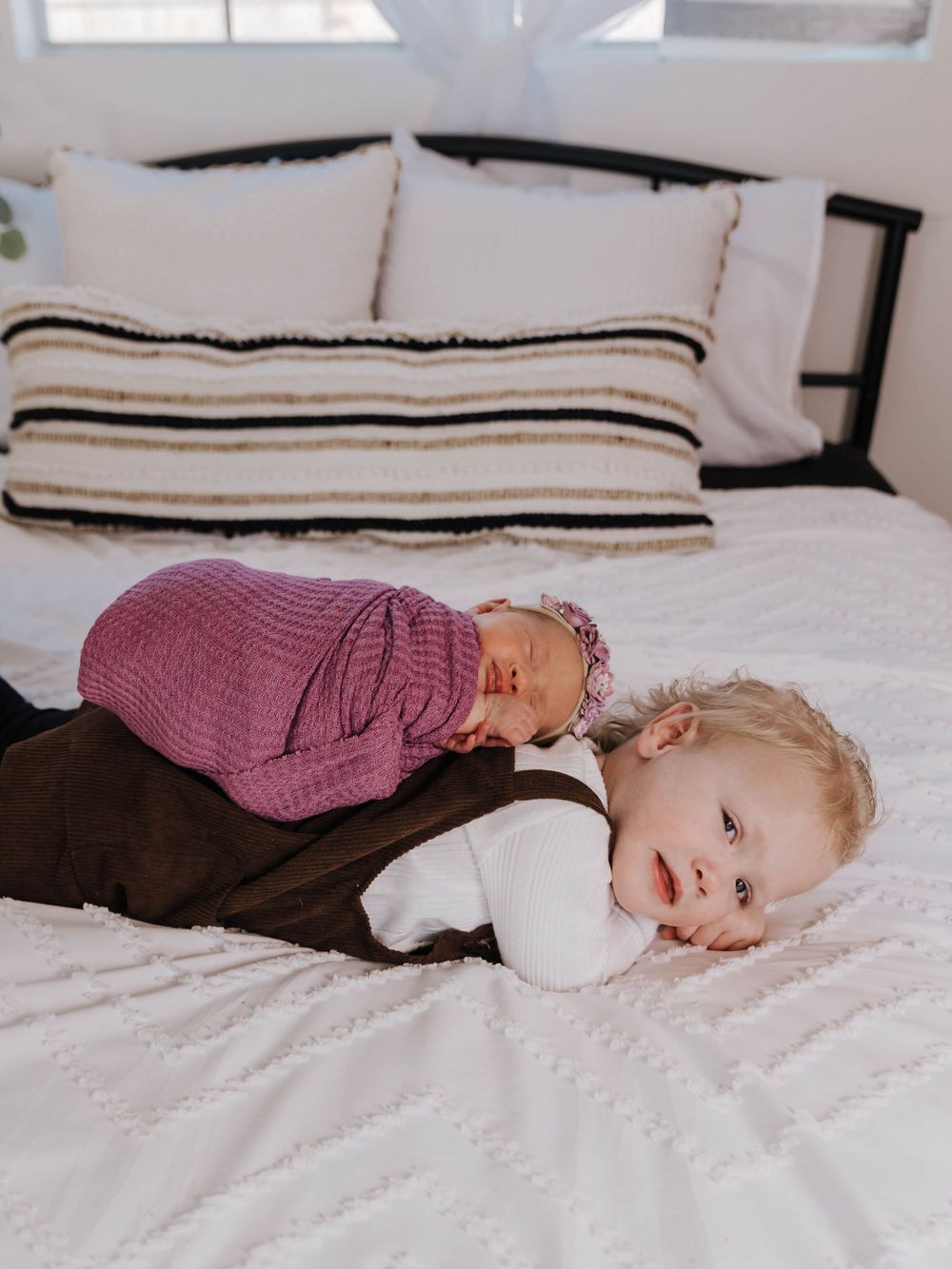 A child in a burgundy sweater lying down on white bedding in a series of connected photos.