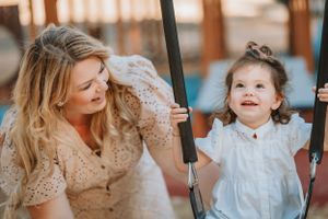 A child smiling with joy while swinging at a playground on a warm sunny evening.