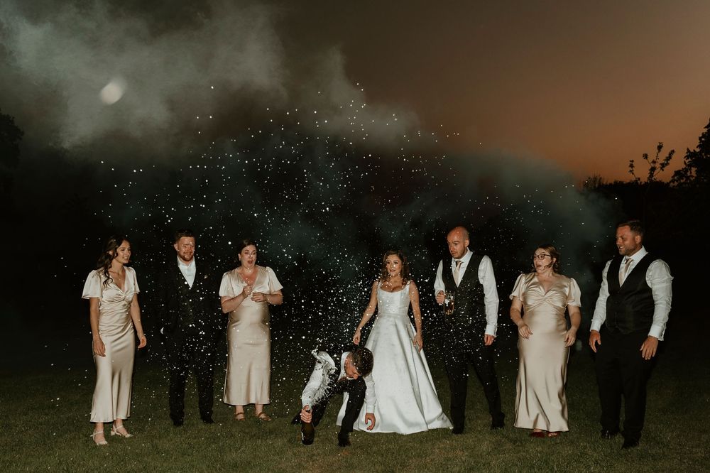 A series of wedding photos showing the wedding party posing at night with sparklers creating a magical effect.