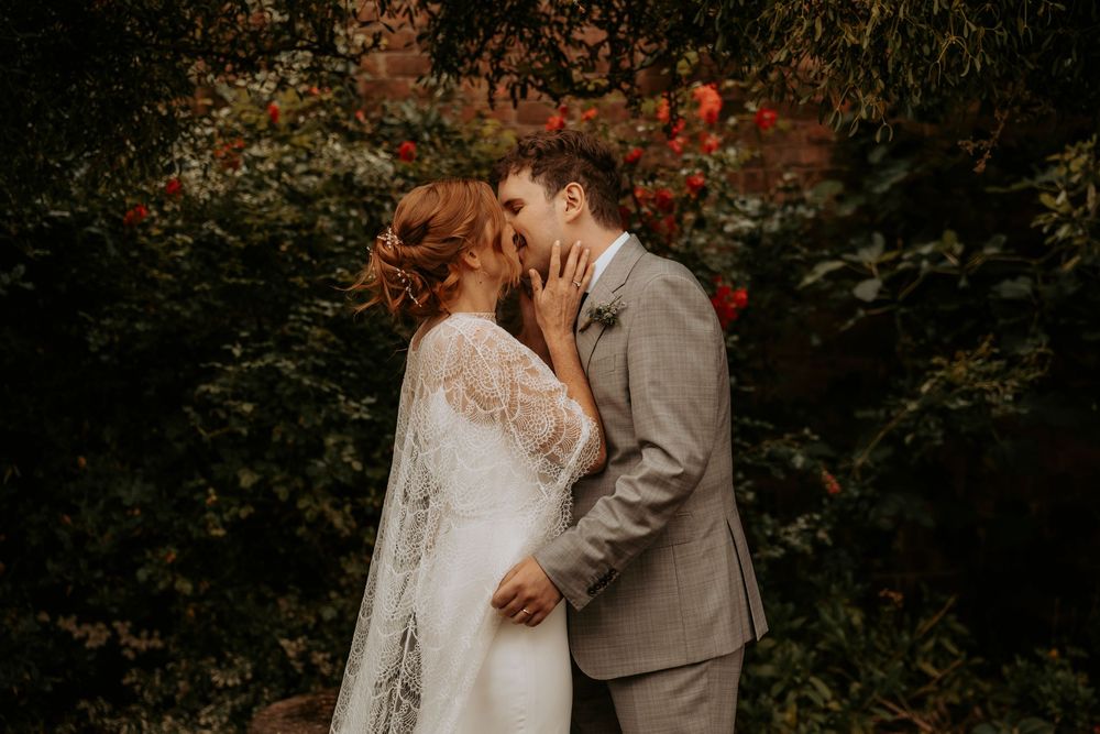 A romantic couple embraces during an autumn wedding photoshoot surrounded by red and orange foliage.