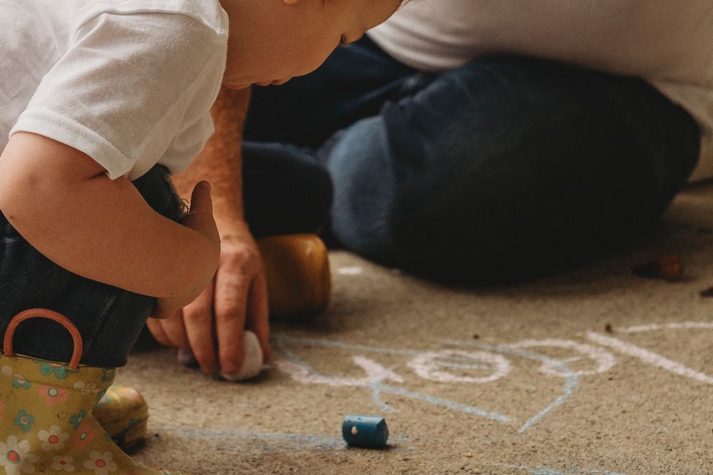 Child drawing with chalk on floor during renovation project.
