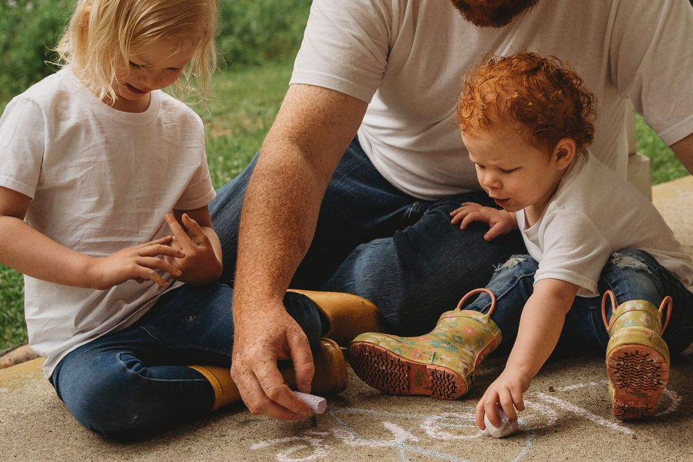 Family doing sidewalk chalk drawings together outside.