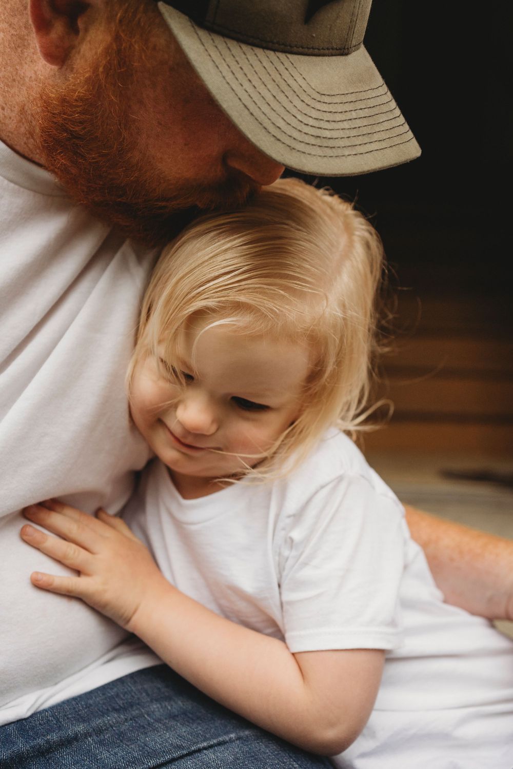 Intimate moment between parent and child in white shirts sharing a tender embrace.