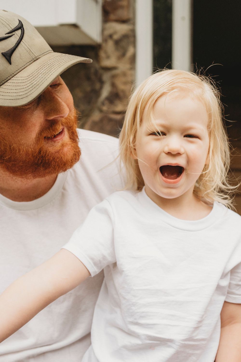 Candid outdoor portrait showing pure joy and laughter on stone porch steps.