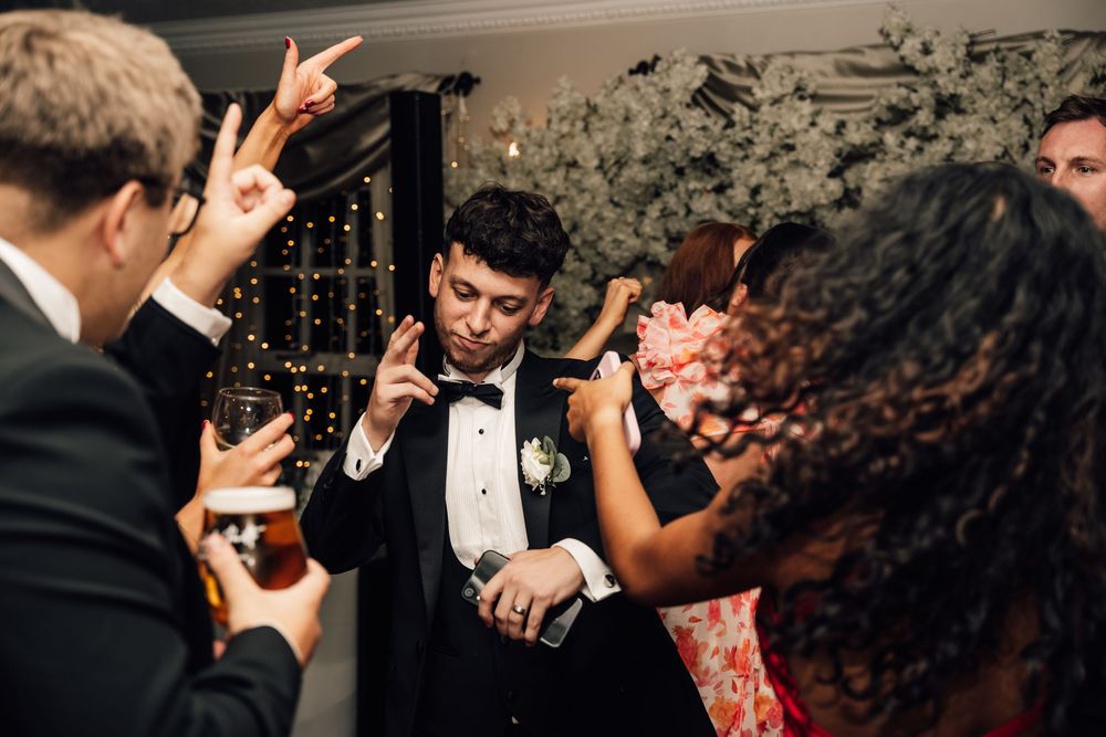Wedding guests dancing and celebrating energetically at an evening reception.