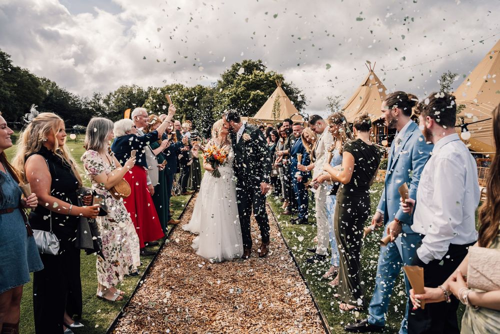 Wedding guests throwing confetti during a joyous outdoor celebration.