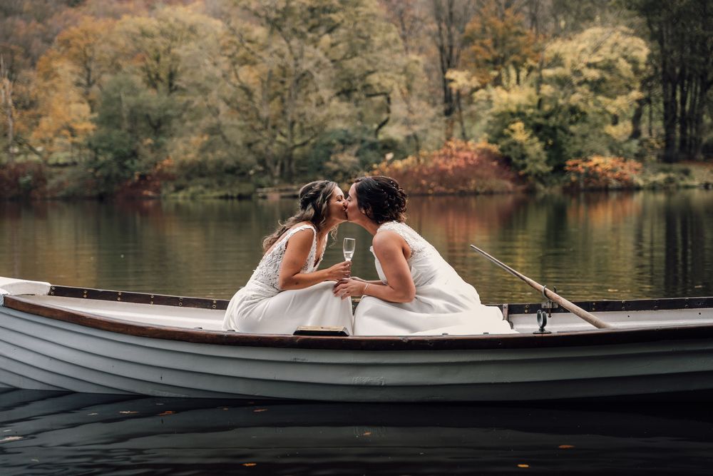 Couple sharing intimate moment by lakeside during autumn wedding photoshoot.