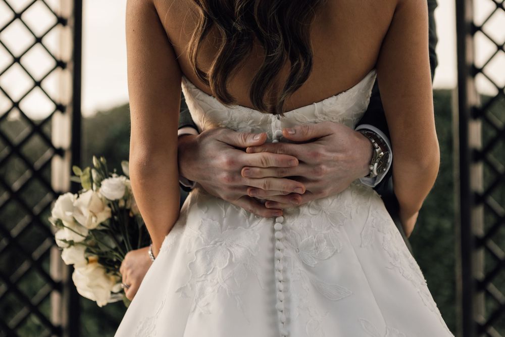 Detail shot of wedding dress buttons and lace on bride's gown.