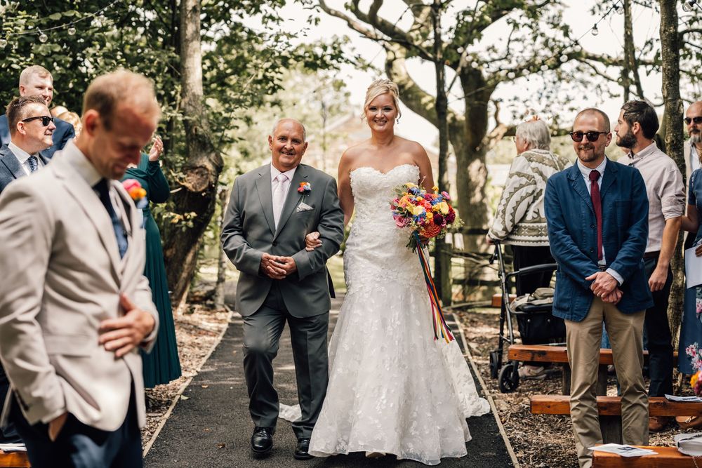 Wedding party and guests mingling in outdoor garden reception area.