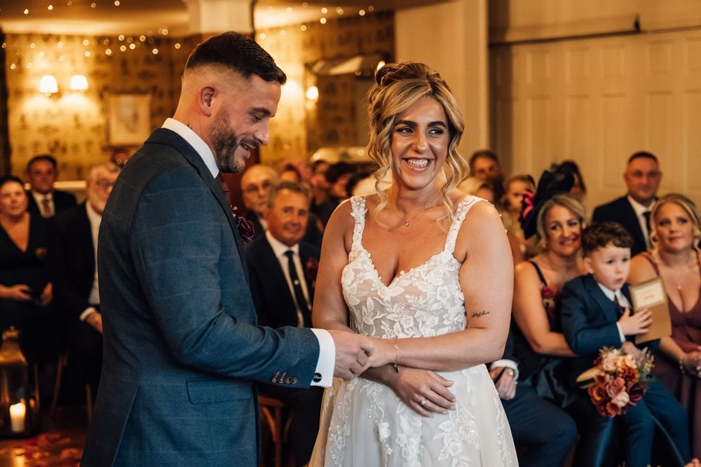 A romantic wedding ceremony moment captured in a warmly lit indoor venue.