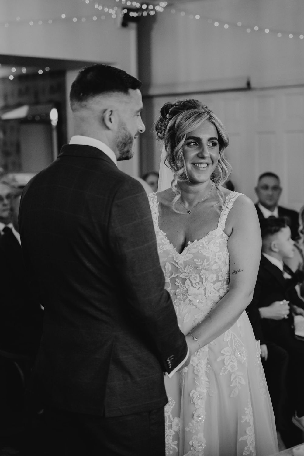 An intimate black and white wedding ceremony moment under twinkling lights.