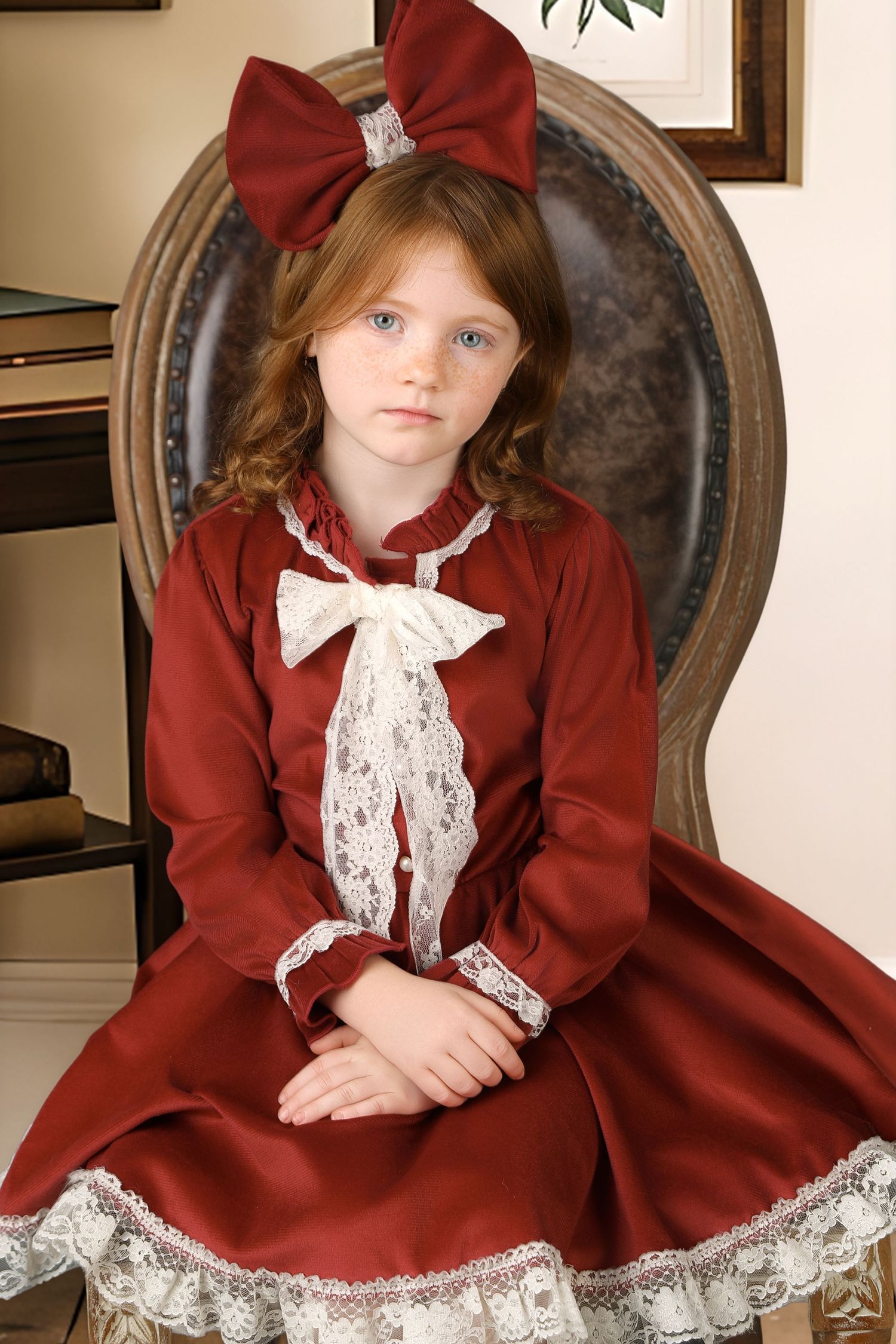 Young girl in plaid blazer and skirt with white tights and black bow headband, posing playfully.