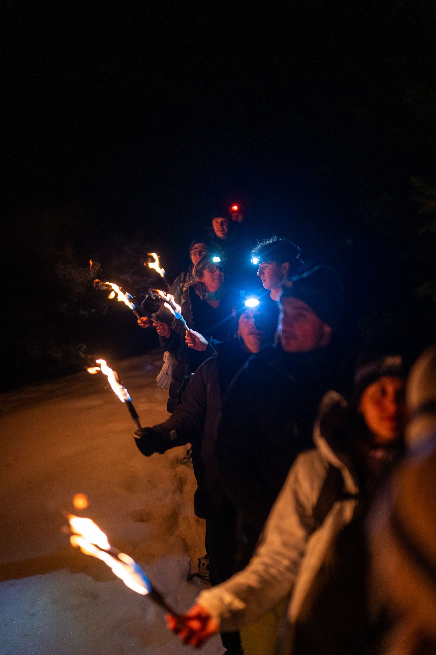 Photo d'un groupe, torche à la main lors d'une randonnée vers le village d'igloo à Annecy