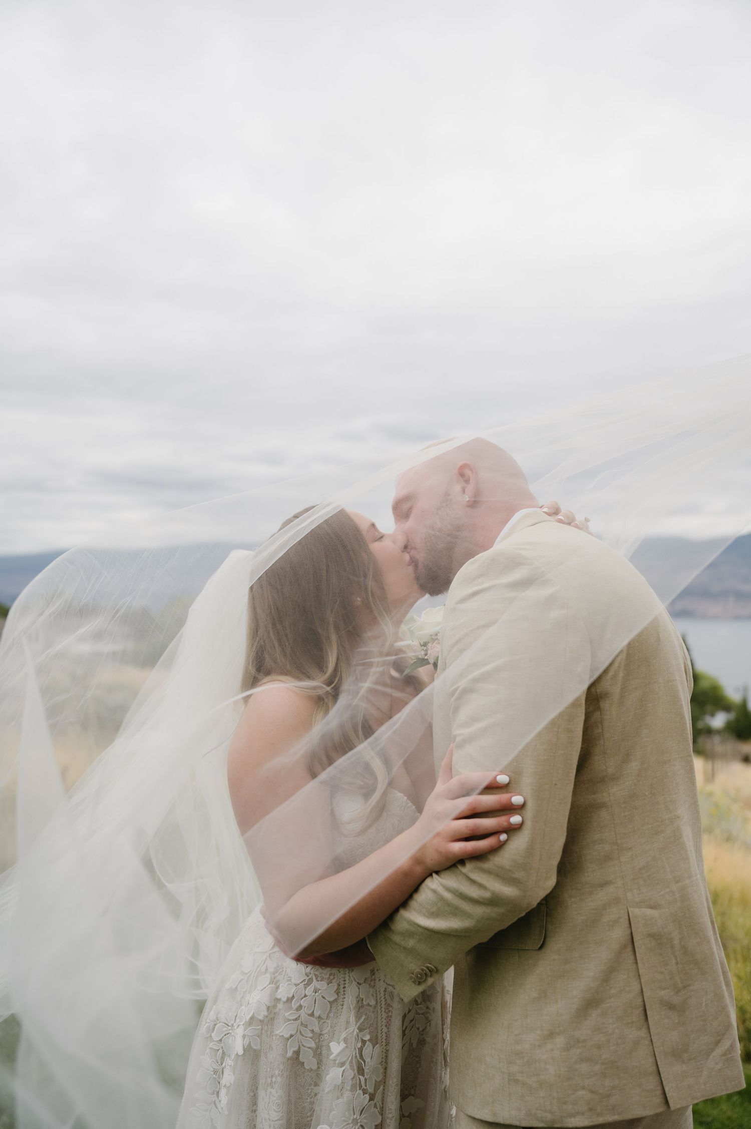 Bride and groom embracing at golden sunset with scenic mountain valley backdrop.