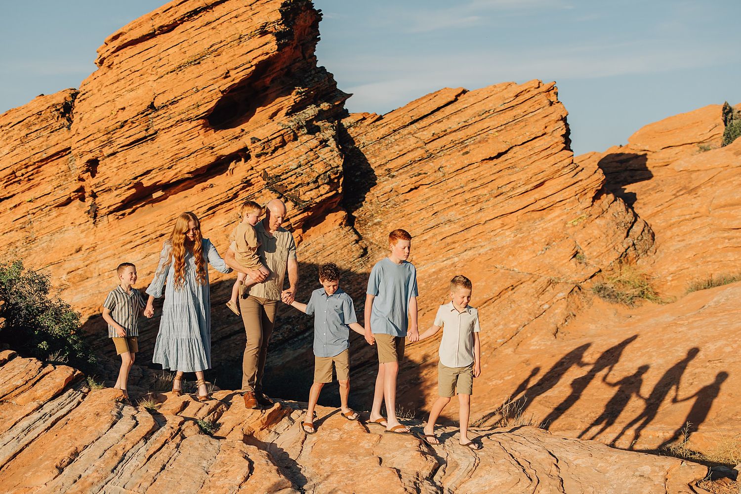 Family of six children and mother posing on red rock formations at Red Rocks Park, Colorado, in matching blue outfits.