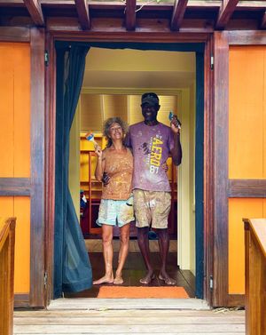 Two paint-covered people smiling in a colorful doorway after a fun painting project together.
