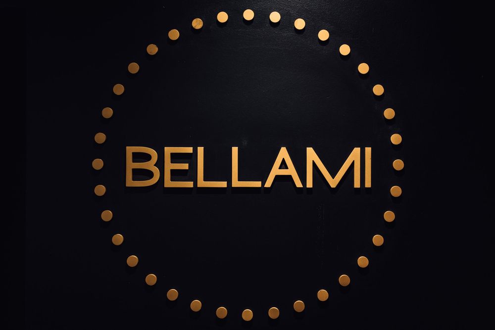 Bellami brand logo in gold letters surrounded by circular gold dots on a black background.