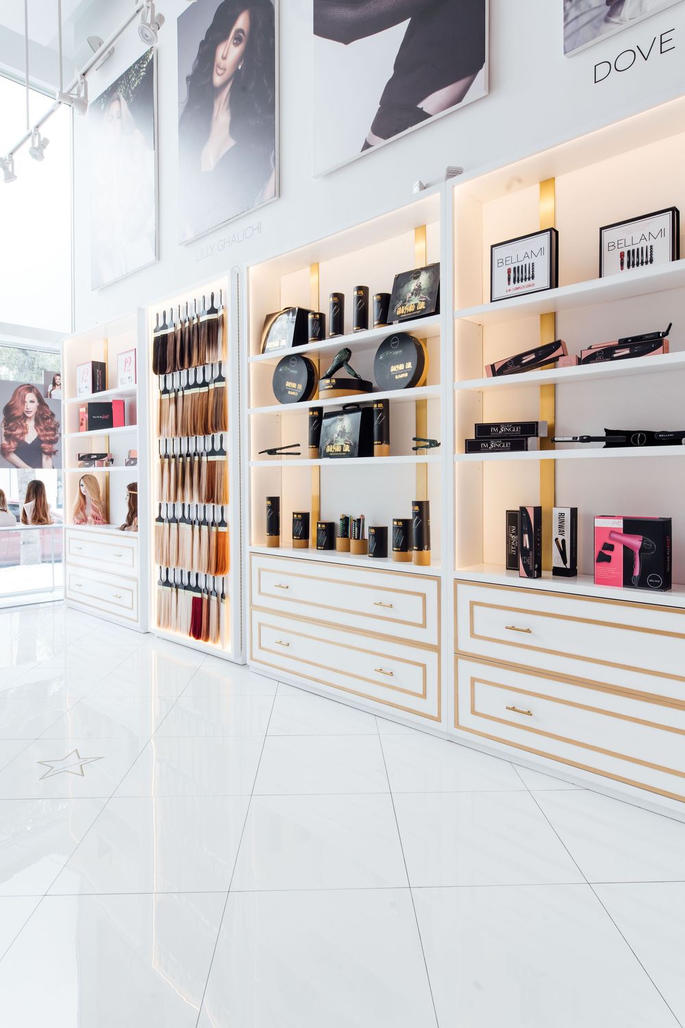 Modern hair salon retail display with white and gold shelving showcasing professional hair care products and color swatches.