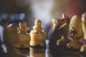 Close-up of vintage ivory chess pieces including pawns and a knight on a board.