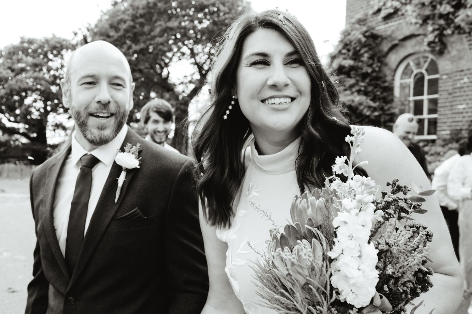 A large group of people, including a bride and groom, posing together outside a building.