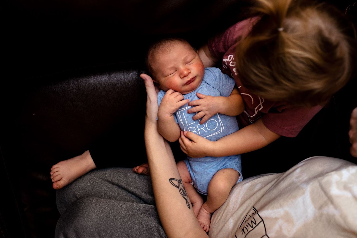 Intimate moment showing gentle care of newborn baby in dimly lit setting.