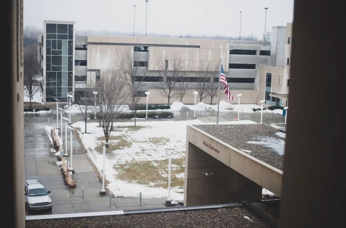 Snow-covered parking lot with modern building and American flag in winter.
