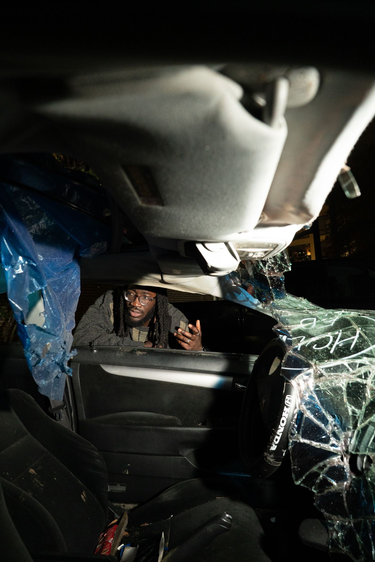 Interior view of damaged car with shattered windshield at night.