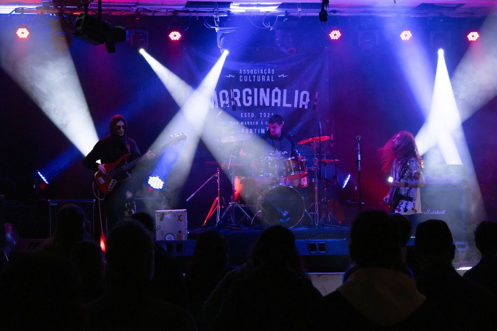 Band performing on stage at Marginalia cultural event with dramatic blue and white stage lighting.