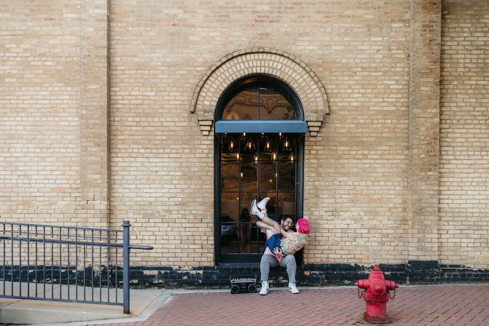 Couple embracing in front of a rustic brick building entrance with arched doorway in West Dundee, Il during engagement session