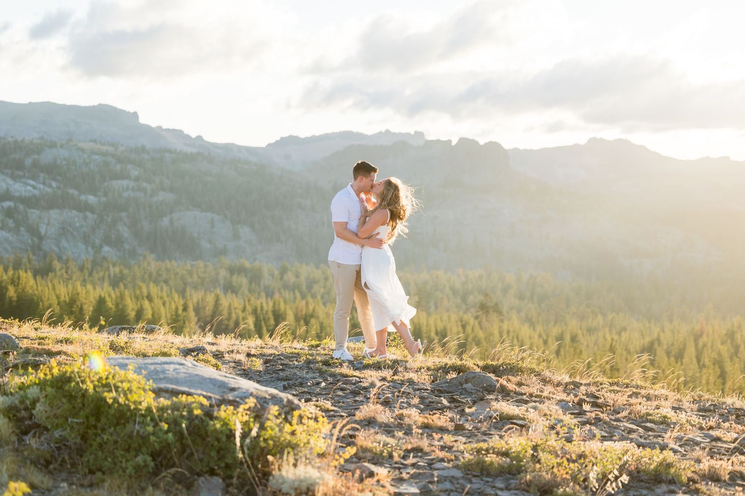 Couple holding hands and walking on green grass in front of lush bamboo trees, woman in white dress.