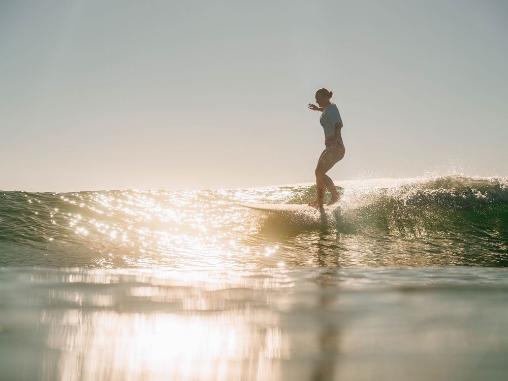Woman with on a longboard in golden light at a surfing competition at Scotts Head, NSW Loggerheads