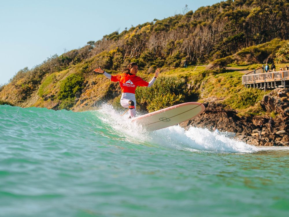 Woman with a competition jersey with a stylish drop knee turn at a surfing competition at Scotts Head, NSW Loggerheads