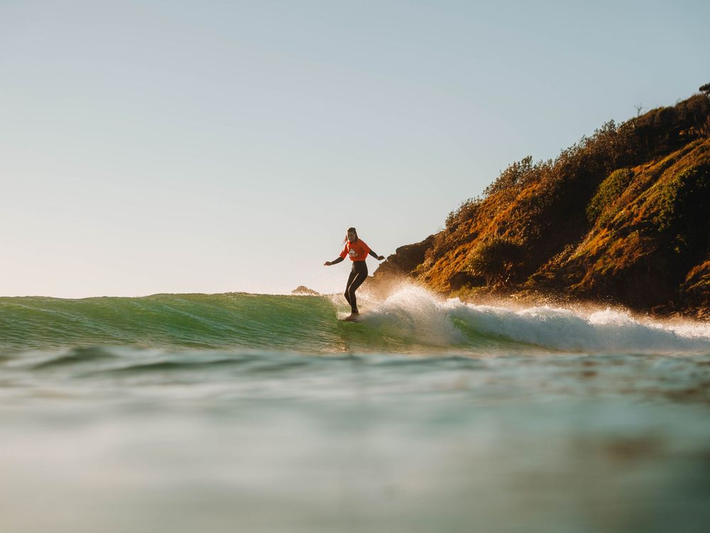 Woman with a competition jersey hang 10 on a longboard at a surfing competition at Scotts Head, NSW Loggerheads