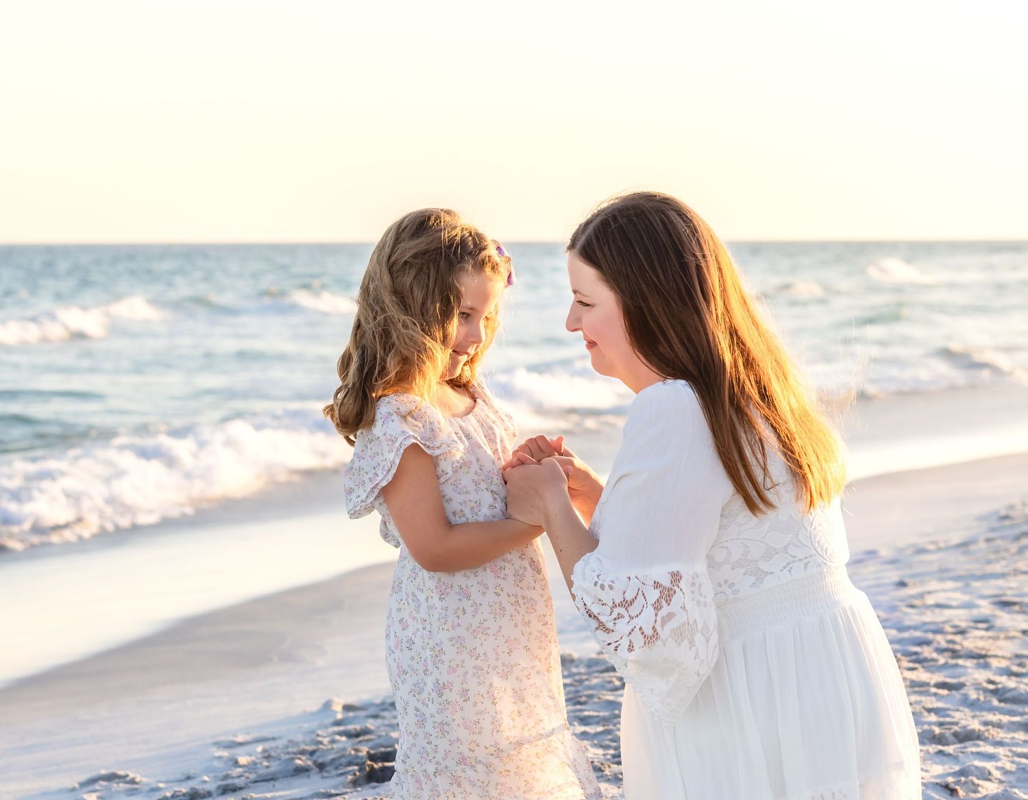 Family of four enjoying a golden hour beach walk, with grandparents and two young children playing by the ocean waves.