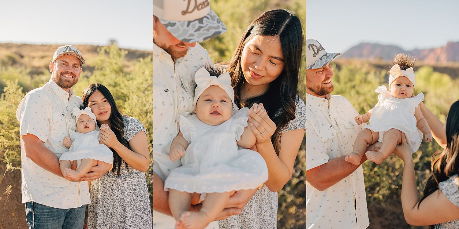 Happy family with baby girl posing outdoors in desert landscape, parents smiling in casual white outfits.