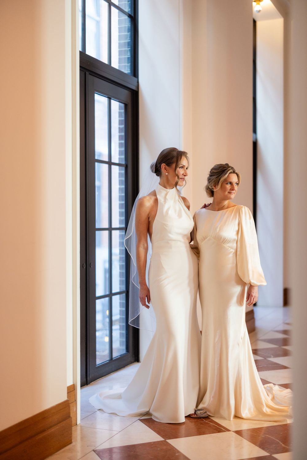 Two beautiful brides looking into their ceremony space at Shinola hotel hallway