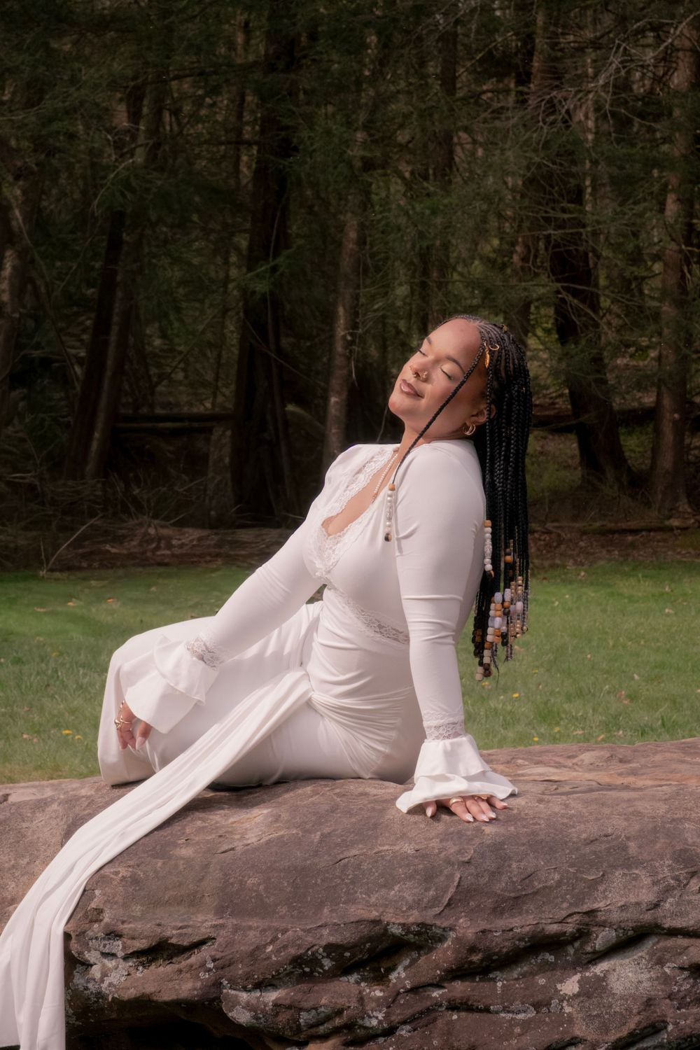 A woman in a white dress with long braids sits gracefully on a rock in a lush forest setting.

Uniontown, PA