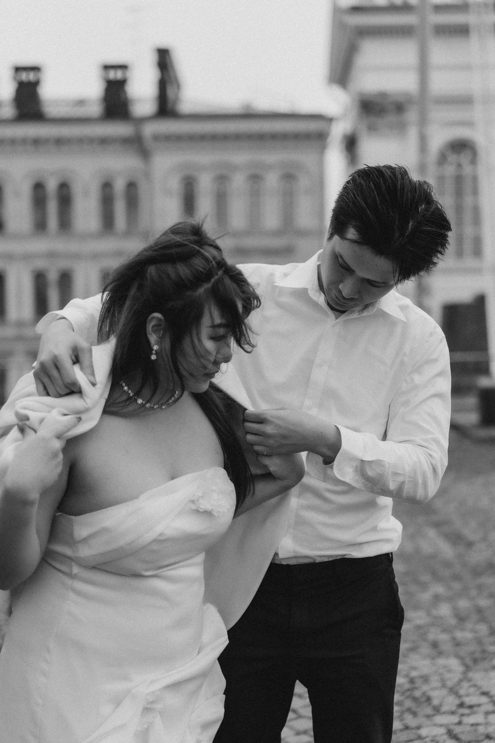 Black and white engagement photo of a couple laughing together at Senate Square in Helsinki