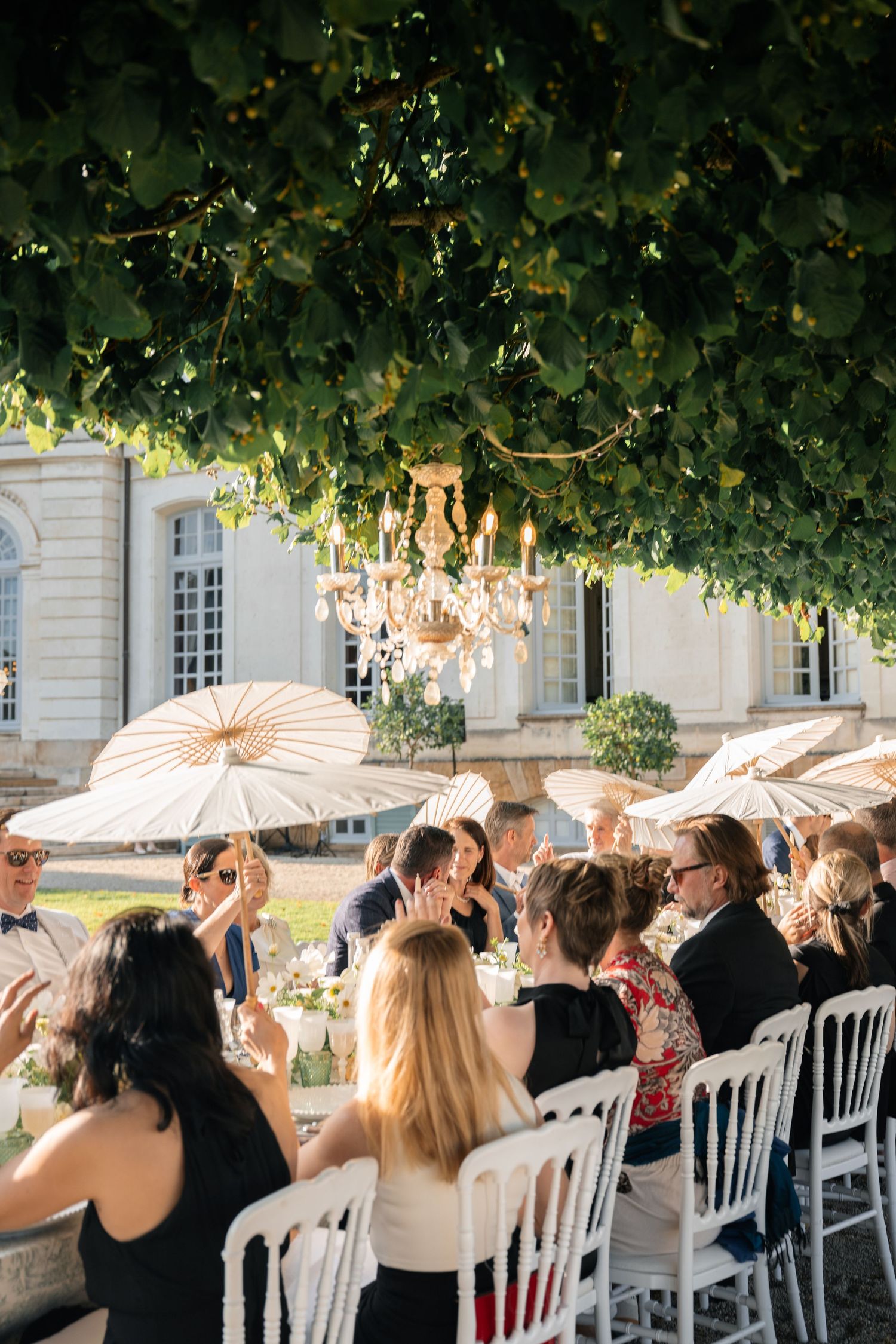 Elegantly dressed guests watch golden fireworks light up the night sky at an outdoor evening celebration.