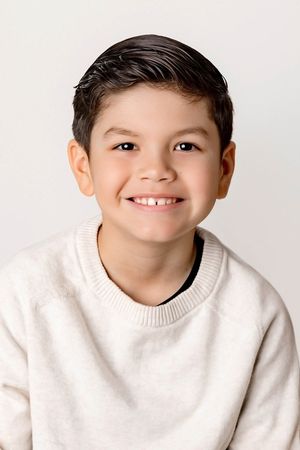 Portrait photographer in Menifee: Smiling dark-haired boy in a cream sweater poses for a cheerful school portrait photo.