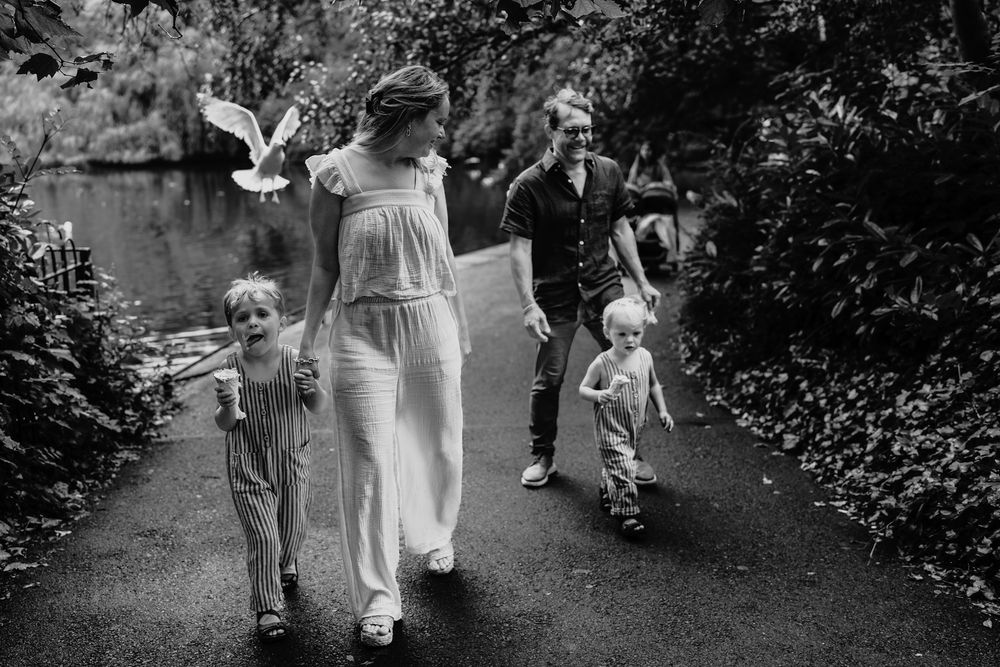 Black and white photo of a family walking on a garden path, with a bird flying nearby.