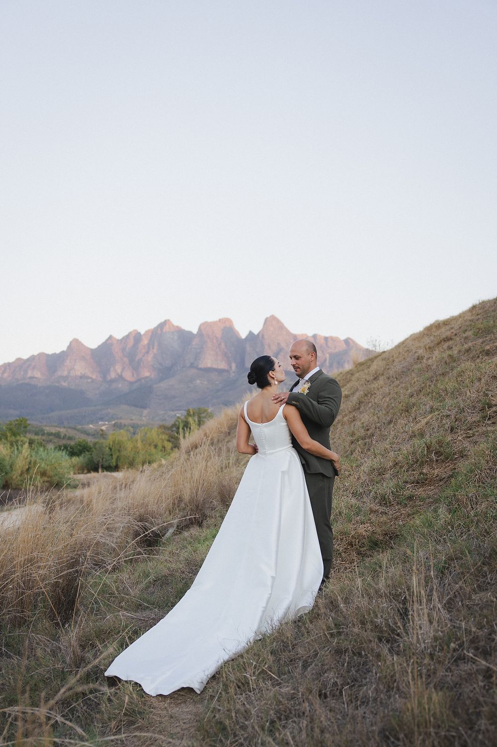 Bride and groom sharing intimate moment beneath sunset skies at Kleinevalleij