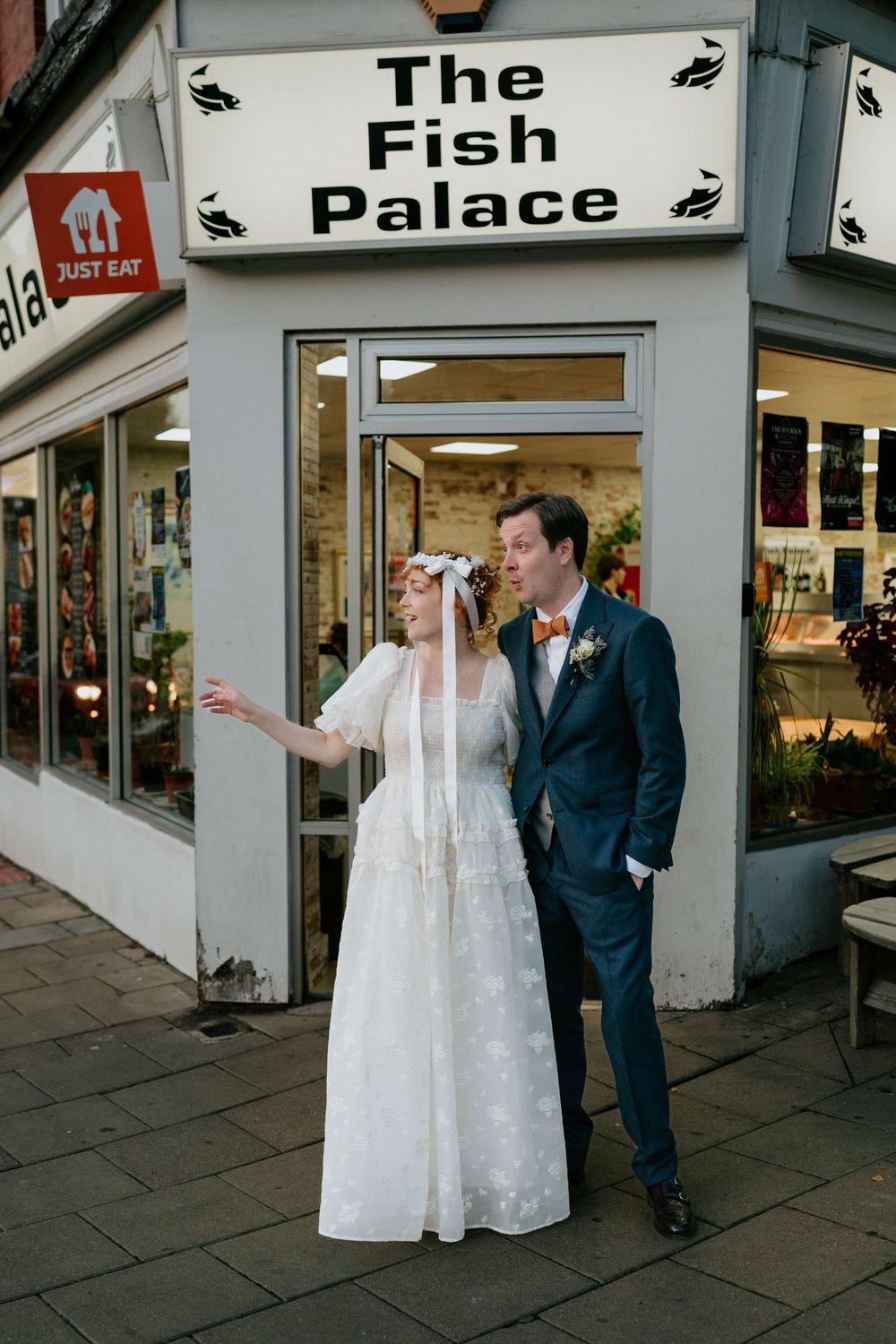 Bride and groom posing outside The Fish Palace restaurant on their wedding day.