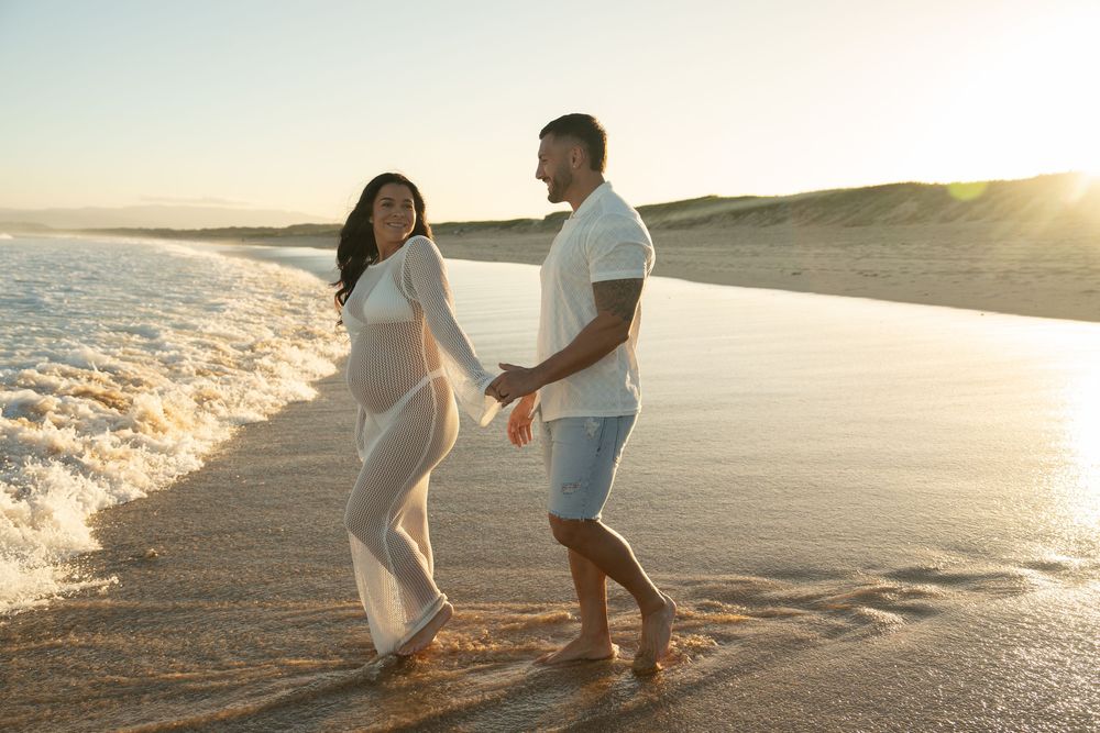 couple holding baby bump during sunset maternity photoshoot