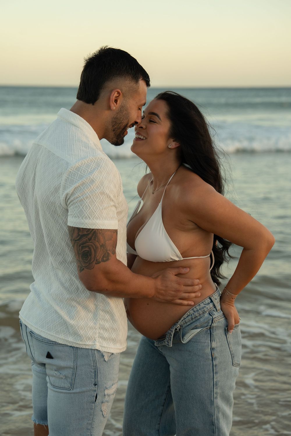 couple walking along beach during maternity photos Wollongong