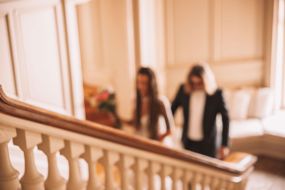 Soft focus artistic shot of bride and groom together near ornate white staircase balustrade.